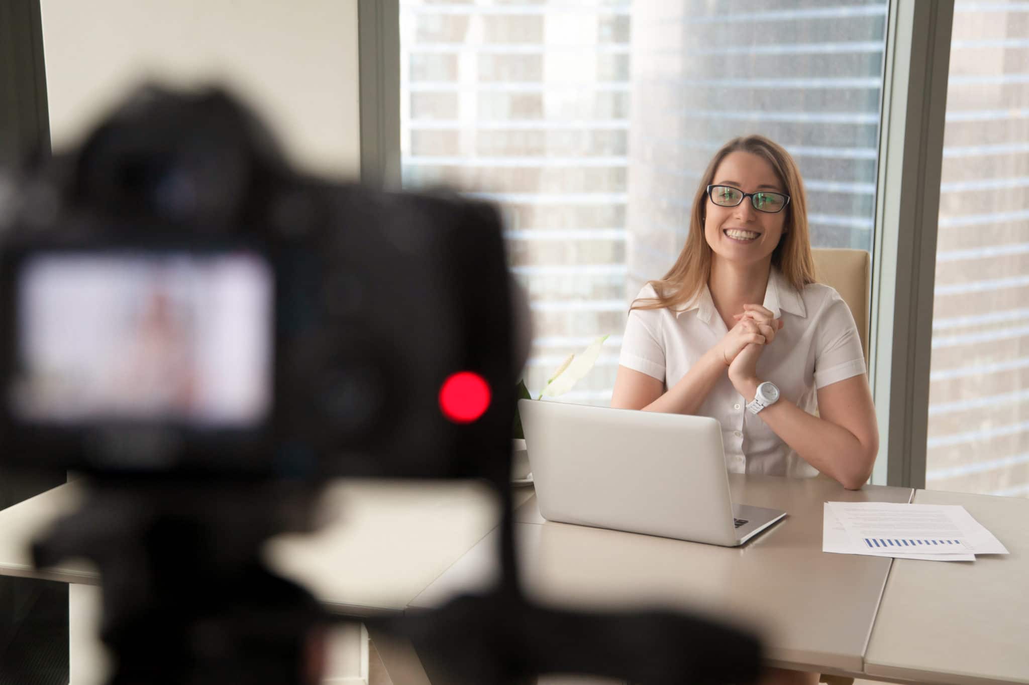 Female customer smiling at desk while video of her presentation being recorded