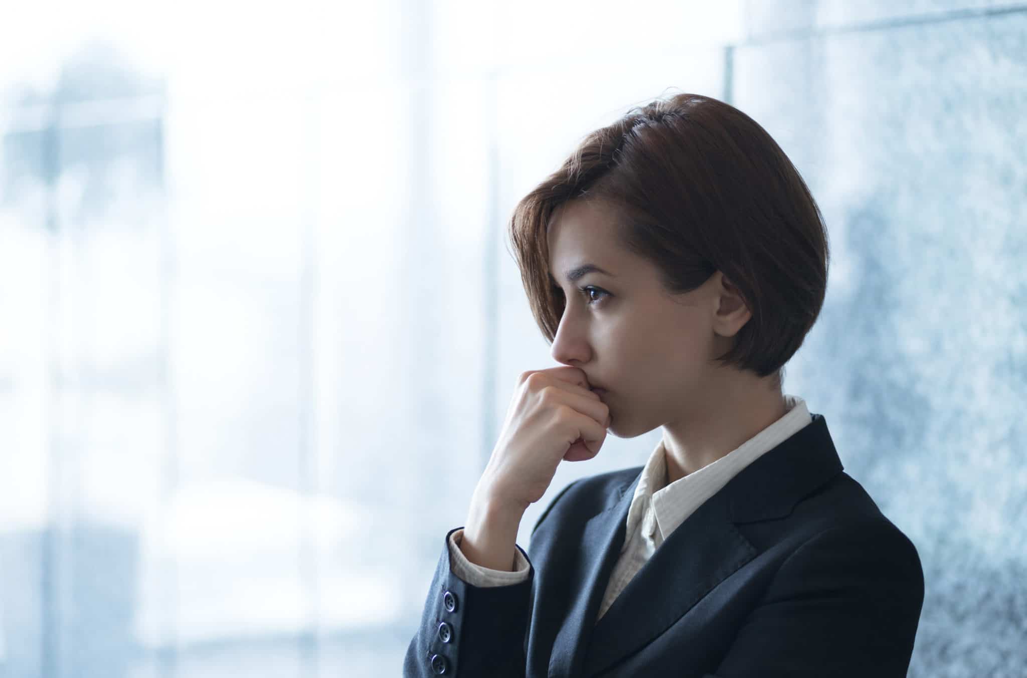 Business women with short dark hair and blue suit seriously pondering a question